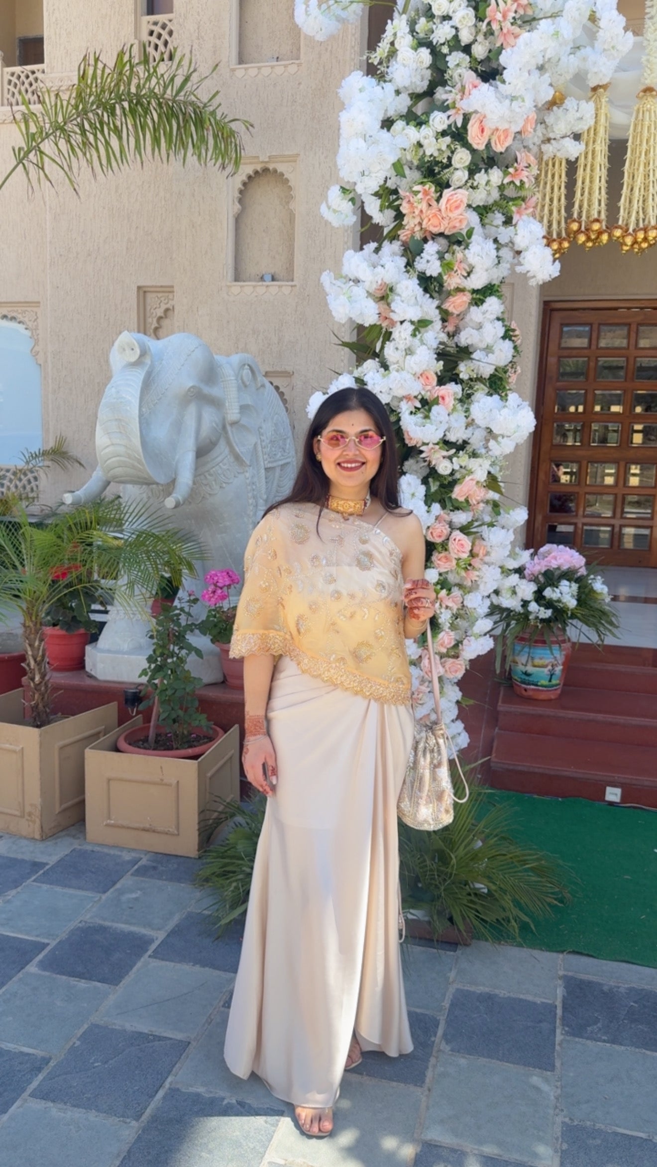 A flowy champagne drape skirt paired with embroidered one shoulder sheer cape blouse, designed to bring together timeless tradition and contemporary style.